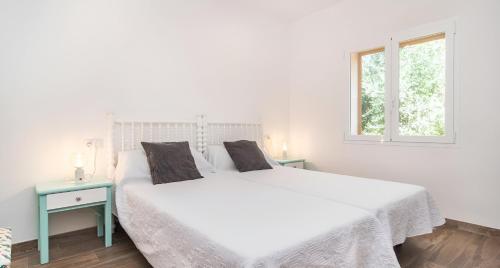 a white bed in a white bedroom with a window at Sa Costa in Campos