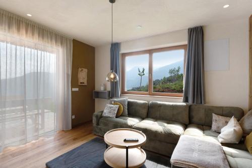 a living room with a couch and a large window at Ratscheinerhof App Gipfelglück in Lazfons