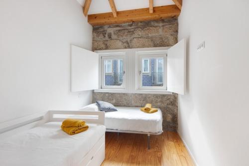 a bedroom with two beds and two windows at Lidador House Vila do Conde in Vila do Conde