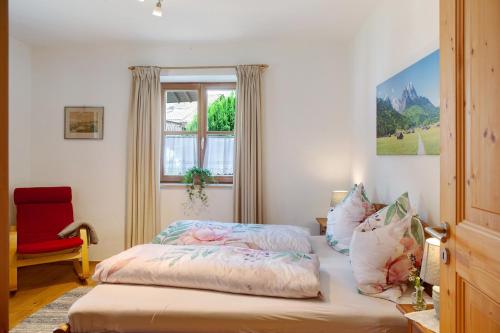 a bedroom with a bed with a window and a red chair at Ferienwohnung Zugspitzblick in Grainau