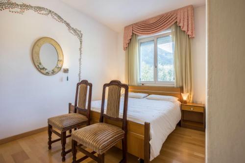a bedroom with a bed with two chairs and a mirror at Casa Zanoni in Arco