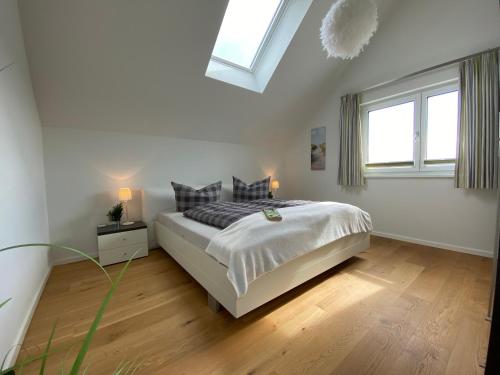 a white bedroom with a bed and two windows at Reeders Topp by Seeblick Ferien in Olpenitz