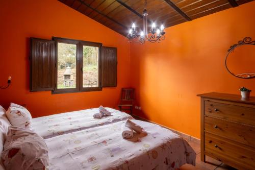 ein Schlafzimmer mit orangefarbenen Wänden, einem Bett und einem Fenster in der Unterkunft Aitxitxe in Karrantza