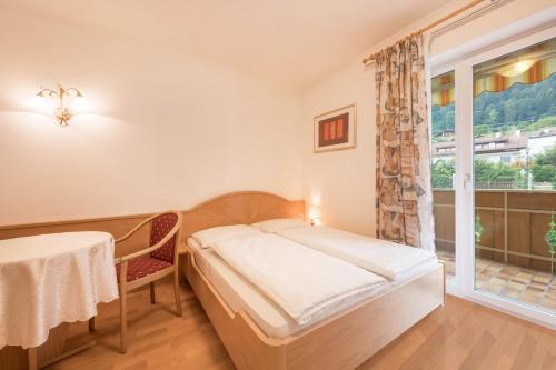 a bedroom with a bed and a table and a window at Residence Kronstein - Fewo 4 in Tesimo