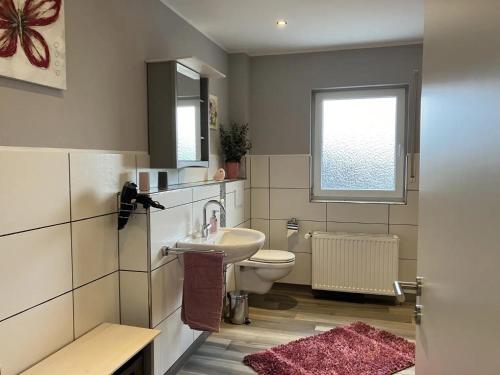 a bathroom with a sink and a toilet and a window at Ferienwohnung Sauerlandherz in Lennestadt