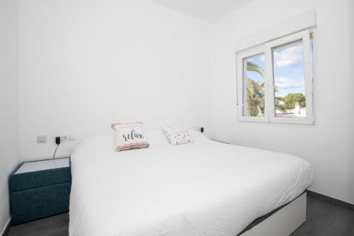a white bedroom with a white bed and a window at Apartamento Marei 3 in Cala Blanca