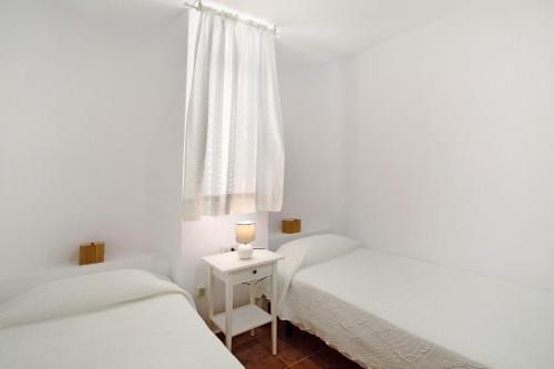 a white bedroom with two beds and a candle on a table at Casa Boti in Puerto Rico de Gran Canaria