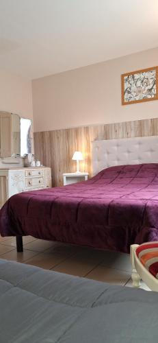 a bedroom with a large bed with a purple blanket at Domaine de Meslay in Fyé