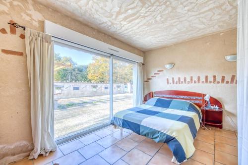 a bedroom with a bed and a large window at La Grange in Guizengeard