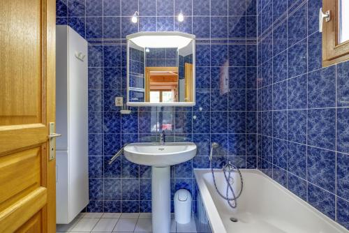a blue tiled bathroom with a sink and a bath tub at Maison entre Lac et Océan in Biscarrosse