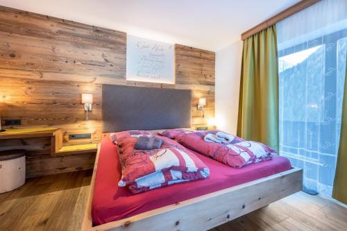 a bedroom with a red bed with a wooden wall at Heiserhof App Apfel in Racines