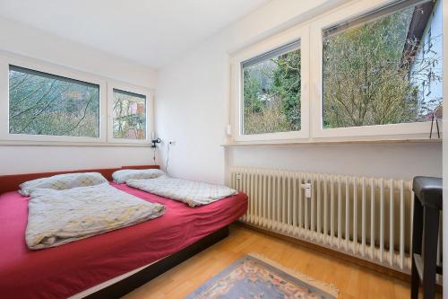 a small bedroom with a bed and two windows at Ferienwohnung Dittmar am Kaffeehof in Bad Liebenzell