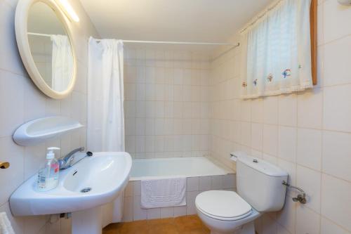a white bathroom with a toilet and a sink at Mastil in Cala Millor