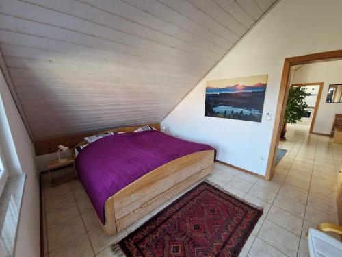 a bedroom with a bed with a purple blanket at Ferienwohnung Storchenblick in Raisting
