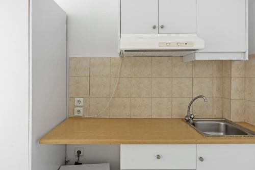 a kitchen with white cabinets and a sink at Evripides family one -bedroom 1 in Kardamaina