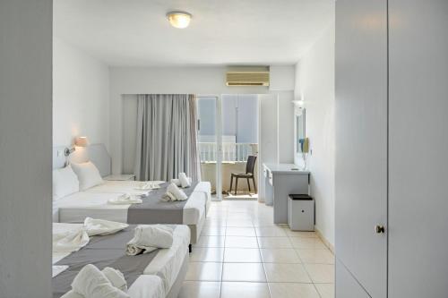 a hotel room with two beds and a desk at Evripides family one -bedroom 1 in Kardamaina