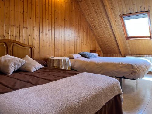 two beds in a room with wooden walls at Casa Rural Los Ciegos in Peguerinos