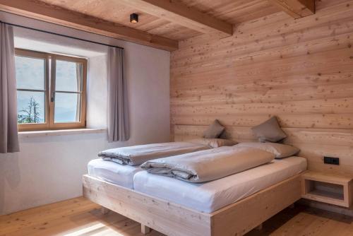 a bed in a wooden room with a window at Egger an der Lahn - Apt Dolomiten in San Genesio Atesino