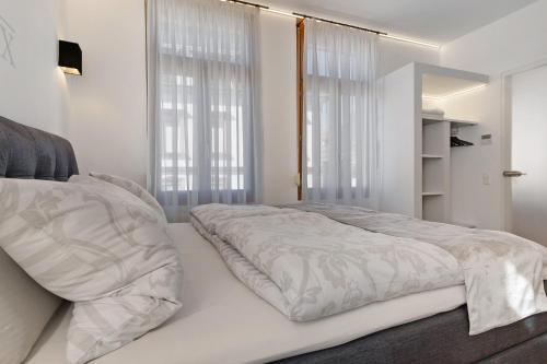 a white bedroom with a large bed and windows at Breisgau Lofts - Nähe Europapark in Herbolzheim