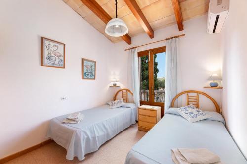 two beds in a room with a window at Can noble den suau in Pollença