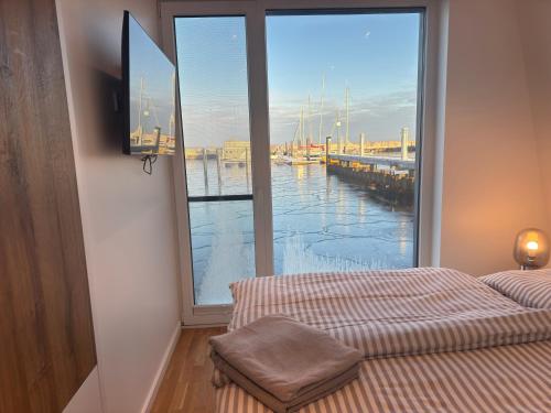 a bedroom with a large window with a view of a marina at Floating Home Nr 1 in Laboe