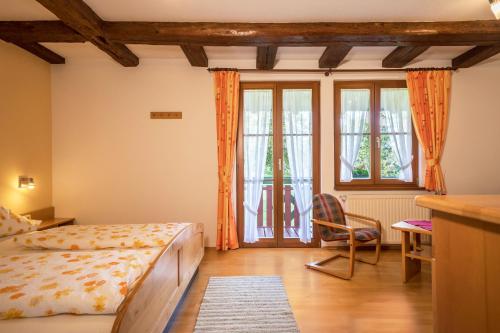 a bedroom with a bed and a chair and windows at Ferienwohnung Risthof 3 in Owingen