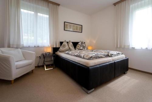 a bedroom with a bed and a white chair at Villa Müller Rotfuchs in Ossiach