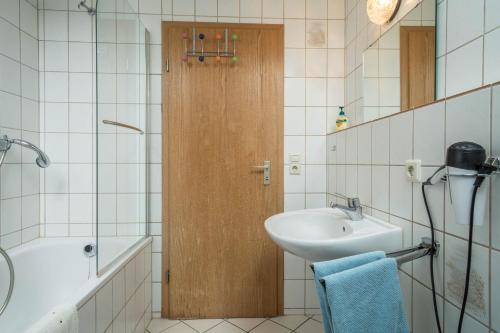a bathroom with a sink and a wooden door at Ferienwohnung Schleinseeblick in Kressbronn am Bodensee