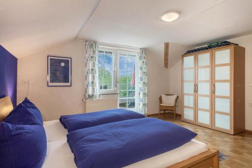 a bedroom with a large blue bed and a window at Ferienwohnung Schleinseeblick in Kressbronn am Bodensee