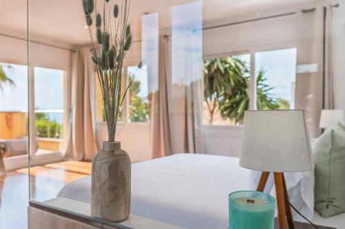 a vase with flowers on a table next to a lamp at Villa Bahia Azul in Llucmajor