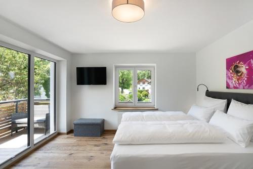 a white bedroom with two beds and a balcony at Ferienwohnung Kalvarienberg in Bad Tölz