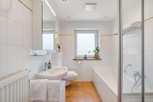 a bathroom with a sink and a toilet and a tub at Ferienwohnung Kalvarienberg in Bad Tölz