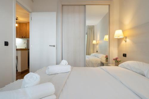 a white bedroom with a large bed and a mirror at Apartamentos Salou - 111 in Salou