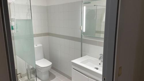 a white bathroom with a toilet and a sink at Retiro Do Tejo in Malpica