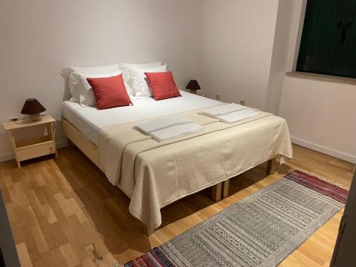 a bedroom with a white bed with red pillows at Retiro Do Tejo in Malpica