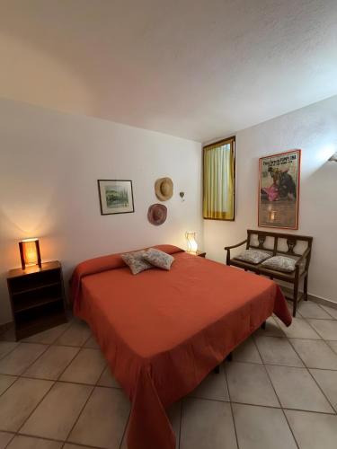a bedroom with a red bed and a chair at Villa Margherita in Marongiu