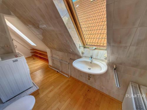 an attic bathroom with a sink and a window at Wohnung 3 in Burghaslach