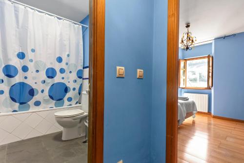 a bathroom with a toilet and a blue wall at Puente del Narcea 2 in Cibuyo