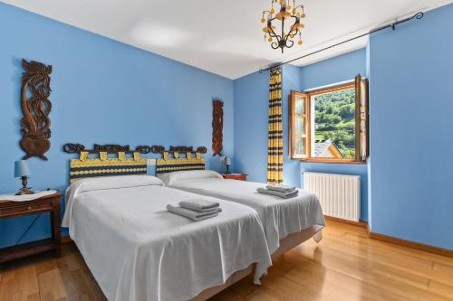 a blue bedroom with a bed and a window at Puente del Narcea 2 in Cibuyo