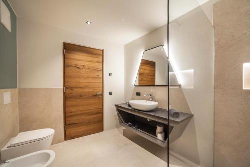 a bathroom with a sink and a toilet and a mirror at Aktiv Lodge Meran - Garden One in San Martino