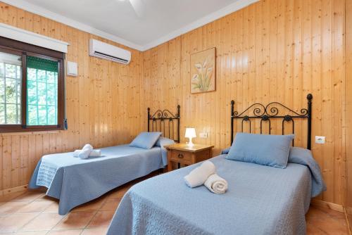 two beds in a room with wooden walls at Casa Rural Salrima in Alora
