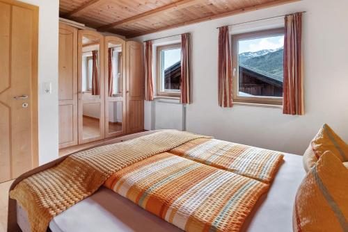 a bed in a room with two windows at New Teindlhof in Curon Venosta