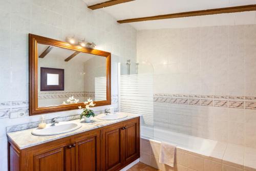 a bathroom with two sinks and a mirror and a tub at Es Figueral in Campos