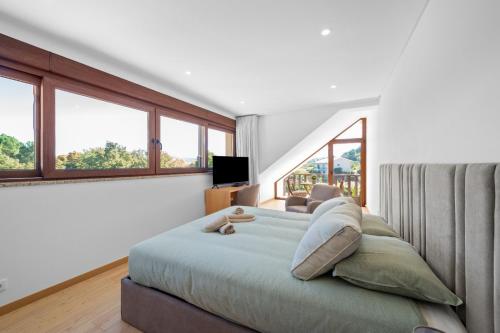 a bedroom with a large bed with windows at Terra Nossa com Piscina aquecida in Vila Real