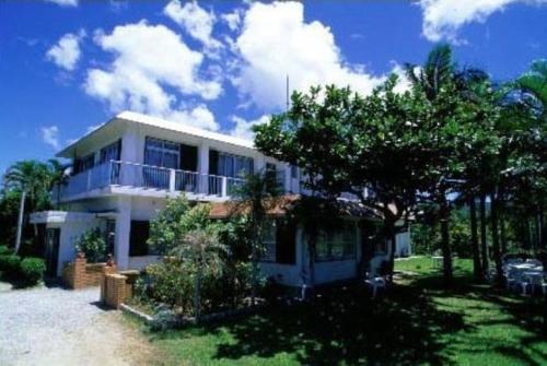 een groot wit huis met een boom ervoor bij Irumoteso in Iriomote