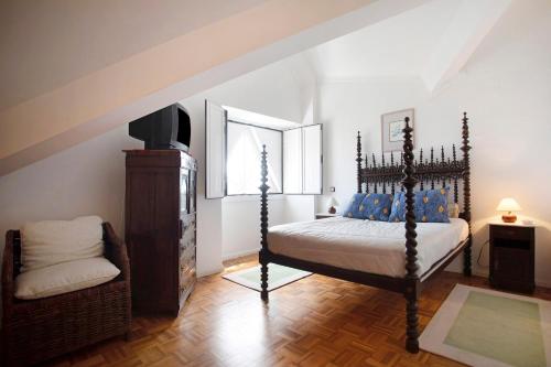 a bedroom with a bed and a tv and a chair at Apartamento Vista Baia in São Martinho do Porto