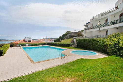a swimming pool in a yard next to a building at Apartamento Vista Baia in São Martinho do Porto