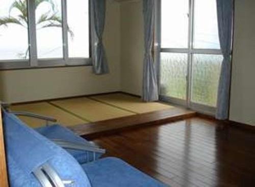 a room with a bed and two windows and a wooden floor at Irumoteso in Iriomote
