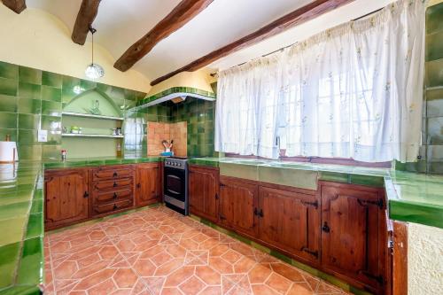 a kitchen with wooden cabinets and green tiles at Casa Pont in Tarragona