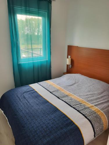 a bed in a bedroom with a blue window at Appartement paisible Richelieu in Chaveignes
